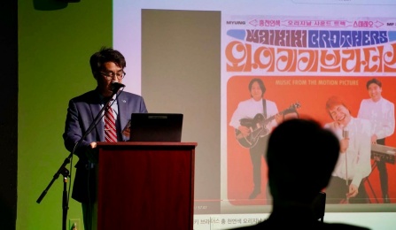 Three people sitting at the front of a room with a screen behind them that says Korean Cinema. 
