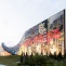 A large, curved installation with colorful images and text, set against a grassy landscape. 
