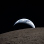 Key Art for the 2025- 2026 Podcast Episodes features the Earthset captured through the Orion spacecraft window at 6:41 p.m. EDT, April 6, 2026, during the Artemis II crew&rsquo;s flyby of the Moon. A muted blue Earth with bright white clouds sets behind the cratered lunar surface. The dark portion of Earth is experiencing nighttime. On Earth&rsquo;s day side, swirling clouds are visible over the Australia and Oceania region. In the foreground, Ohm crater has terraced edges and a flat floor interrupted by central peaks&mdash;formed when the surface rebounded upward during the impact that created the crater. Image Credit: NASA. 