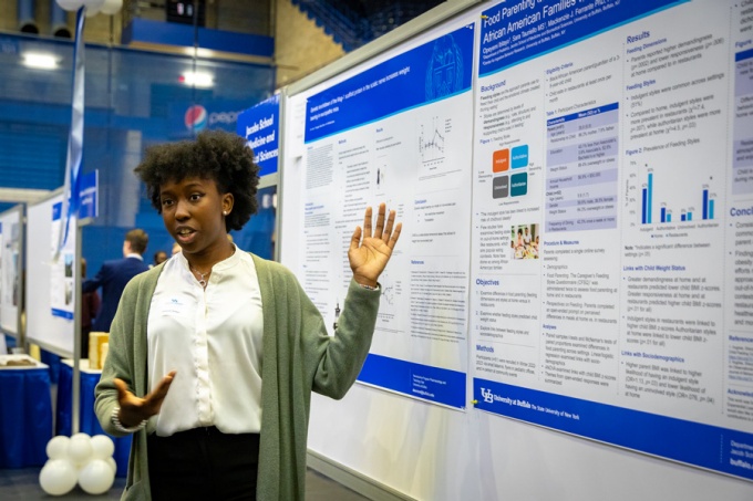 A student presenting a poster that uses UB's research poster template. 
