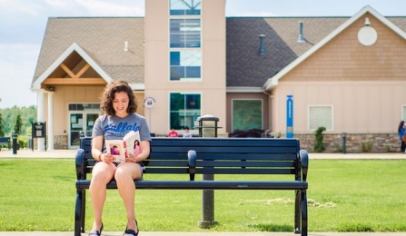 Student reading on a bench outside of North Campus Apartments. 