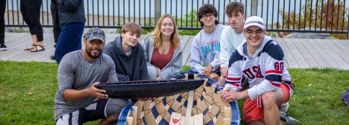 Architecture students pose around a hand made boat. 