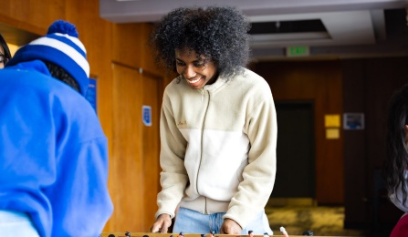 Two students playing foosball in lounge.