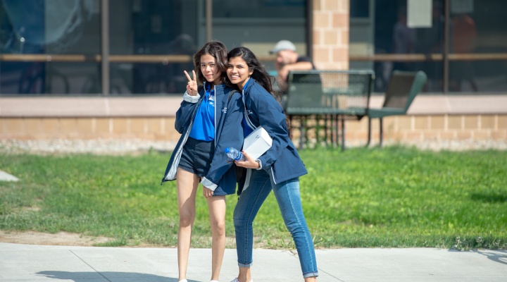 Two student smiling outside a residence hall. 
