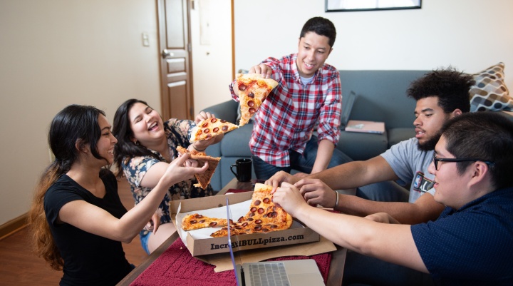 Image of students eating pizza at Flickinger Court apartment. 