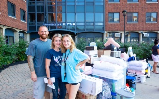 Student and parents standing outside of Goodyear Hall on move in day.