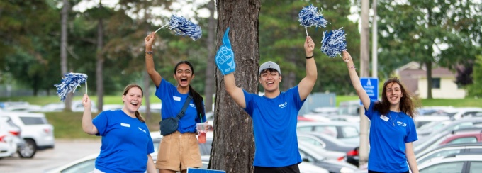 Students in UB blue shirts with pom poms cheering and welcoming students on move in day.