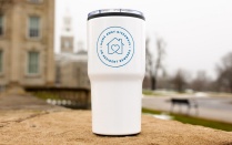 Zoom image: Home Away Giveaway tumbler posed on outside wall with buildings in the back.