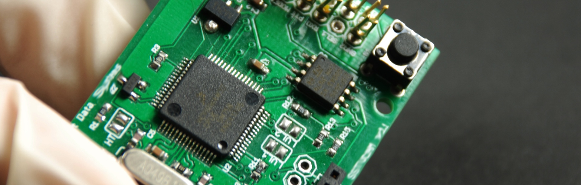 Zoomed in shot of tools (forceps and pointed pen-like object) on top of a computer chip.