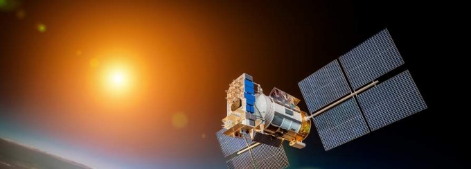 Sattelite floating above Earth's atmosphere with the sun in the background. 