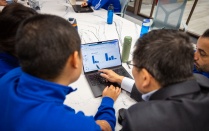 Students huddled around a laptop on a table. 