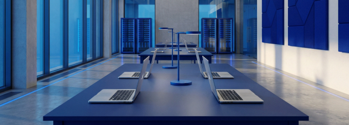 A computer lab with servers in the background and a few laptops on a table. 