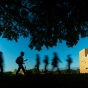 Students walking on North Campus silhouetted by the shadow of a tree. 
