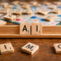 Close-up of a Scrabble-style board game on a wooden table, with scattered letter tiles surrounding a centered tile holder that displays the letters &ldquo;A&rdquo; and &ldquo;I.&rdquo;. 