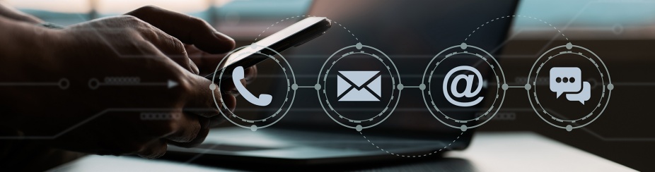 Desk with laptop and hands holding a smartphone. Four icons depicting ways of contacting support including phone, email, and web. 