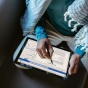 A woman writing on a tablet using a smart pen. 