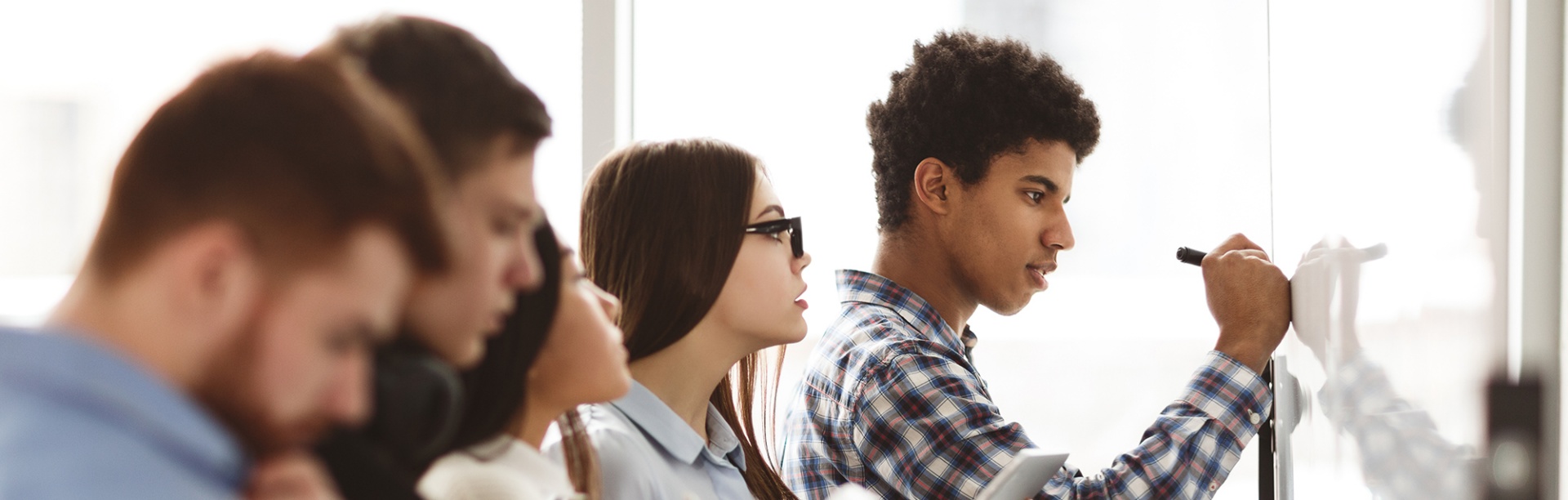Diverse college students working on a white board. 