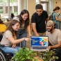 A group of students reviewing digital accessibility on a laptop in a library. 