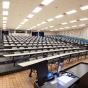 An empty stadium classroom setting brightly lit with natural lighting, the room features accessible technology. 