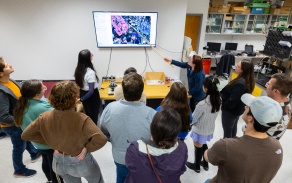 Teaching assistant working with students pointing to a presentation. 