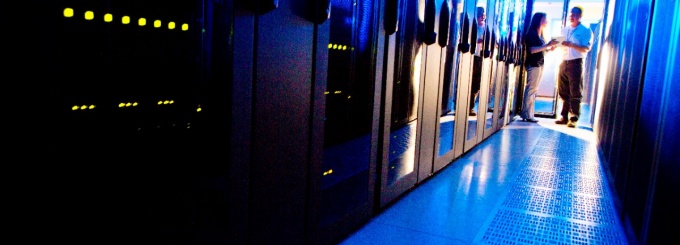 Two technicians in data center with rows of server racks. 
