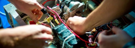 Two people's hands working on a robot. 