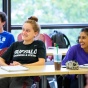 Students sitting in a classroom, smiling and laughing. 