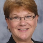 Portrait of Susan Ott smiling into the camera, wearing glasses. 