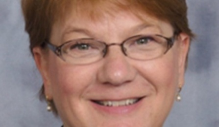 Portrait of Susan Ott smiling into the camera, wearing glasses. 