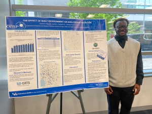 Student intern standing next to their research poster. 