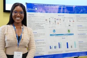 Student intern standing next to their research poster. 