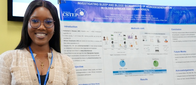 Student intern standing next to their research poster. 