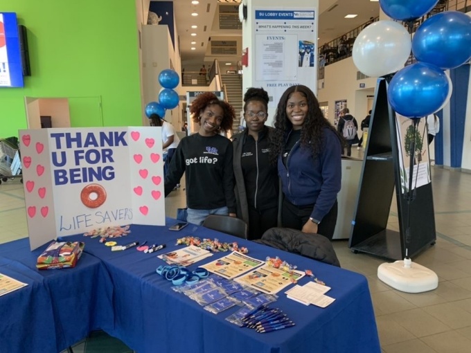 Students standing in the student union, posing for a picture during the organ donor registry and blood drive campaign. 
