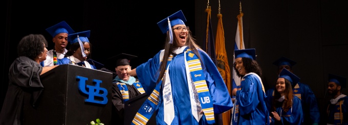 A graduating student walking across the stage to receive her diploma during the ALANA celebration. 