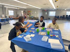 Four students sit around a table, working on an activity. 