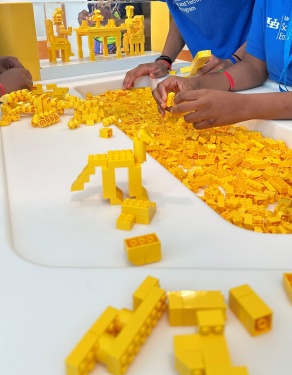 A student's hands in a bin of yellow legos. 