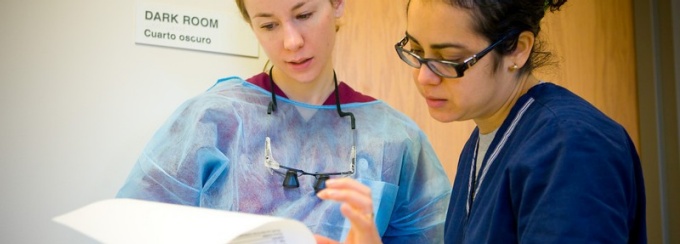 Two Medical professionals, one ina surgial gown and one in scrubs, reviewing medical paperwork. 