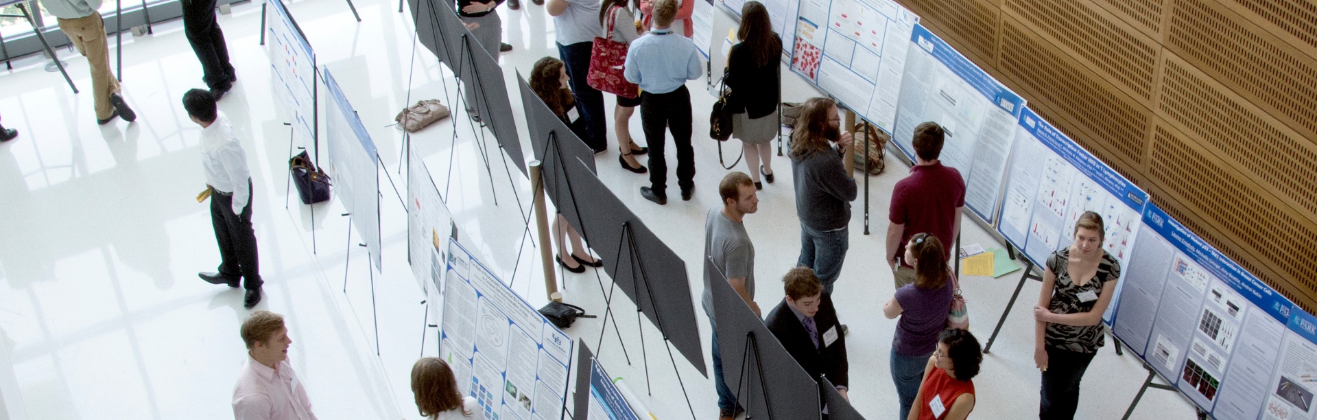 High-angle photo taken at the Clinical and Translational Research Center of attendees at a poster session. Text reads: Mentored Career Development Program Developing an interprofessional and interdisciplinary translational science workforce. 