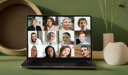Photo of a laptop with a Zoom meeting on screen, on a nicely decorated table against a green wall. 