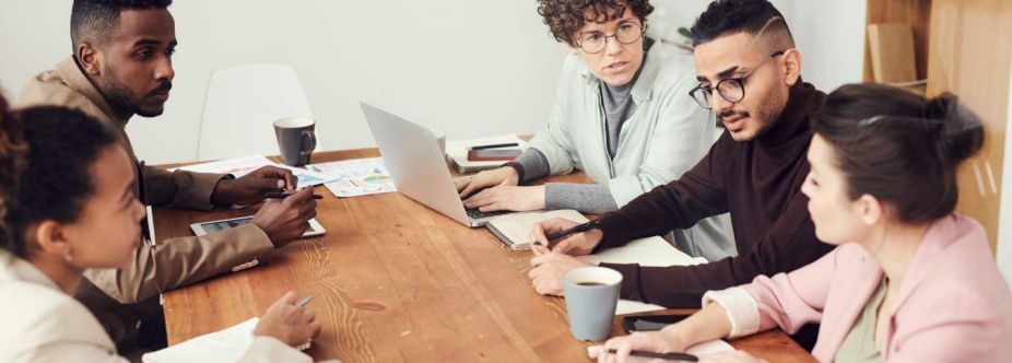 Photo of a group of adults sitting around a table and conversing. 