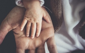 Photo of a small child's hand placed in an adult's hand. 