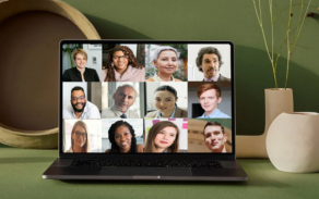 Photo of a laptop with a Zoom meeting on screen, on a nicely decorated table against a green wall. 
