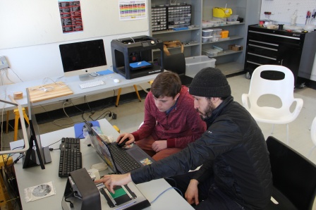 two students in a lab working on a computer at the same desk. 