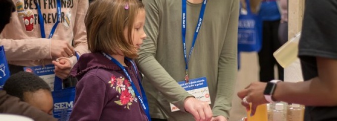 Girls participating at interactive demo tables. 