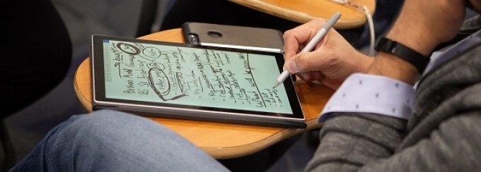 Student writing on a tablet. 