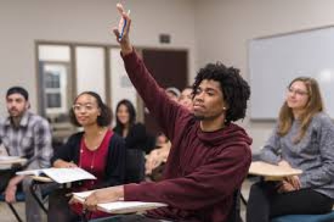 Student raising hand in a classroom. 