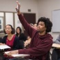 Student raising hand in a classroom. 
