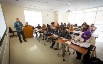 Person standing in front of classroom of students. 
