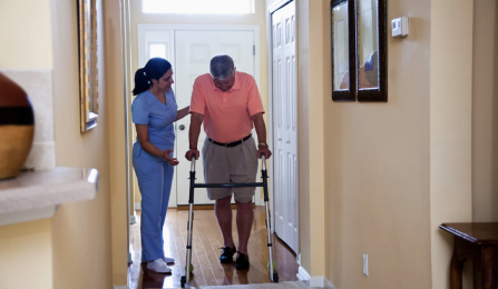 Home Health Aide helping a person walk. 