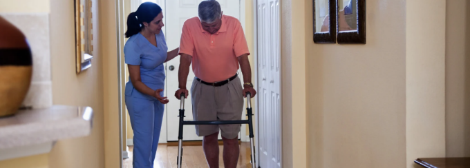 Home Health Aide helping a person walk. 